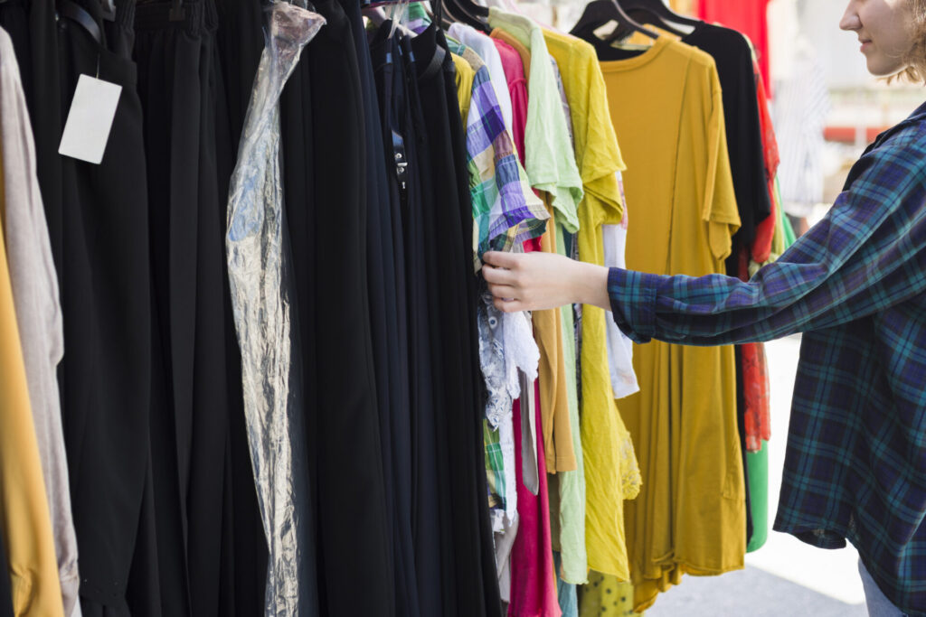 Frau stöbert in einem Kleiderständer
