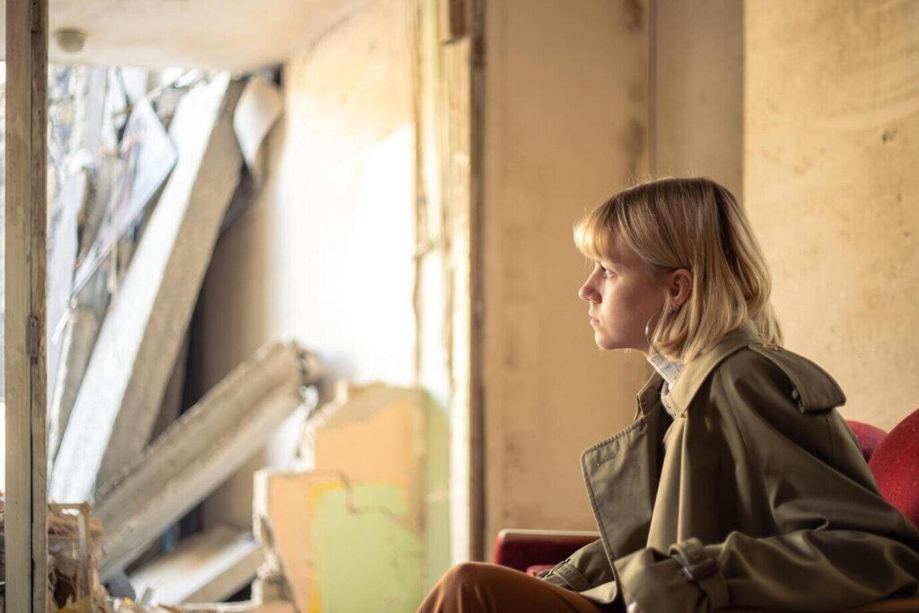 junge Frau in baufälligem Gebäude mit resigniertem Blick