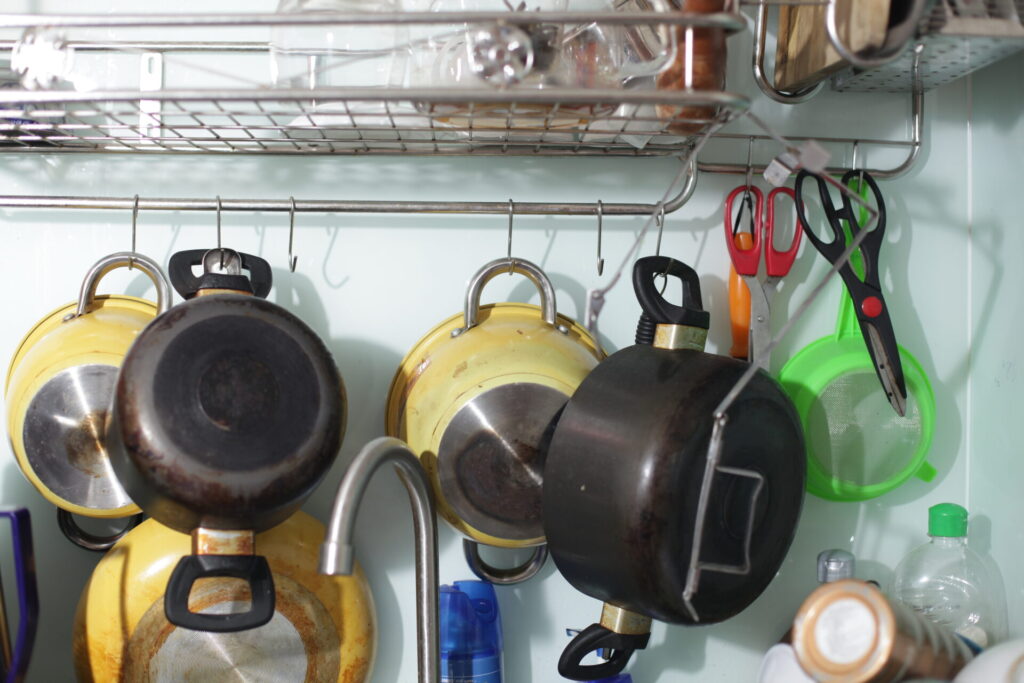 Töpfe und andere Küchenutensilien, die mit Haken an einer Stange hängen